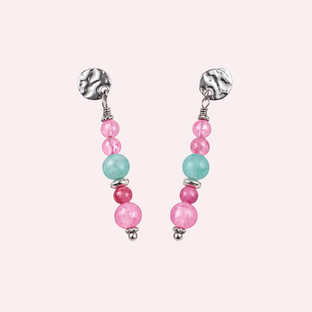 Zilverkleurige oorbellen met gehamerd stekertje en kralen in roze, blauw en fuchsia, op een beige achtergrond