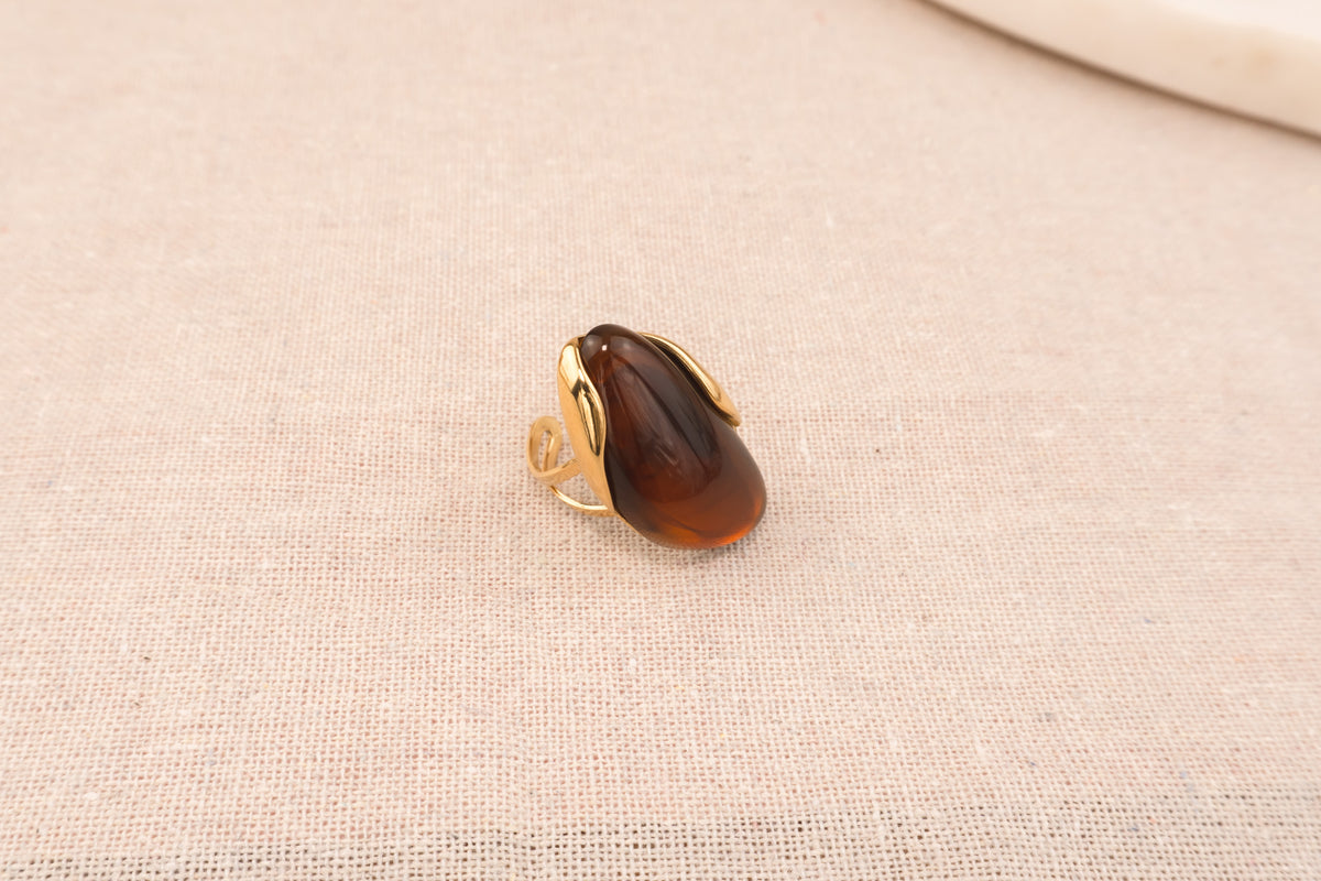 Goudkleurige ring met ovale bruine harsknop, op witte achtergrond