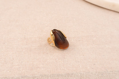 Goudkleurige ring met ovale bruine harsknop, op witte achtergrond