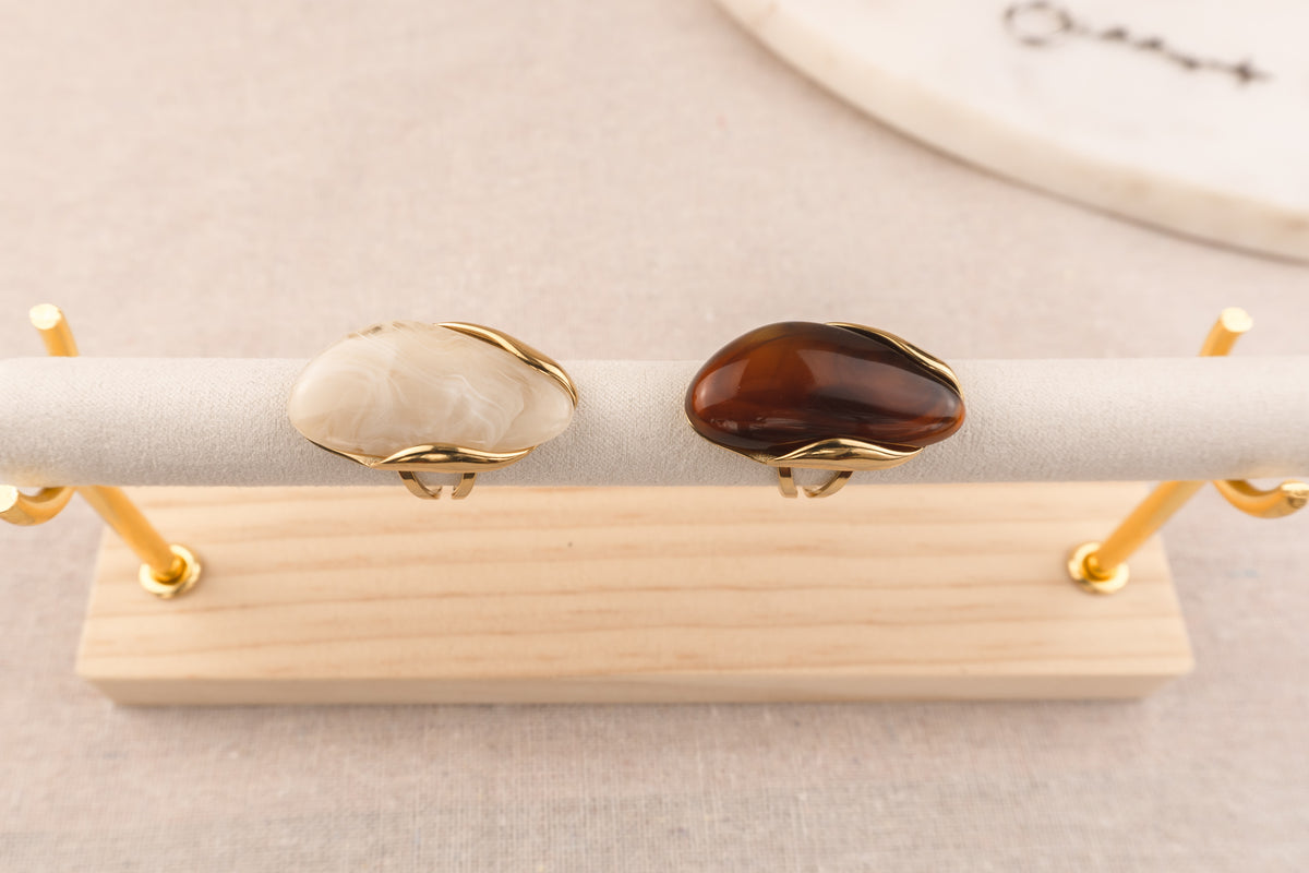 Goudkleurige ring met ovale bruine harsknop, op witte achtergrond