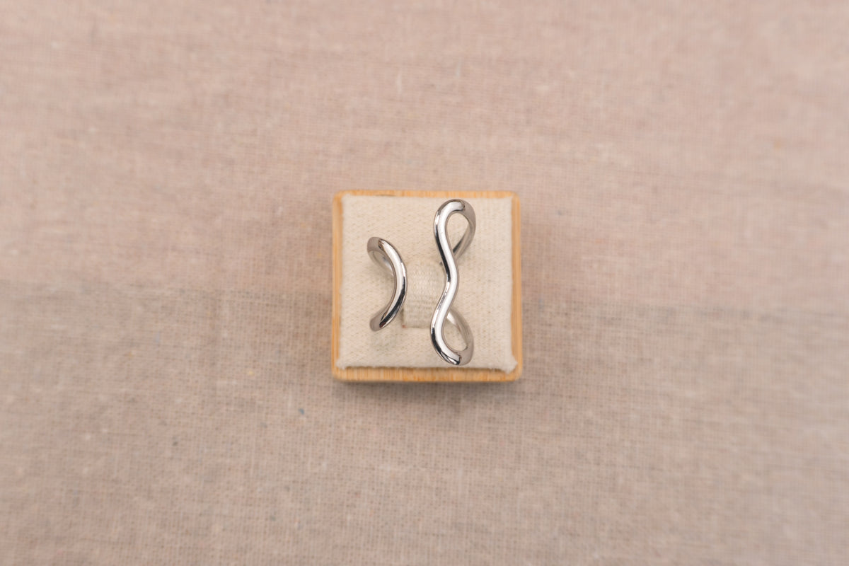 Zilverkleurige open ring met organisch vloeiend gevormde band, op witte achtergrond