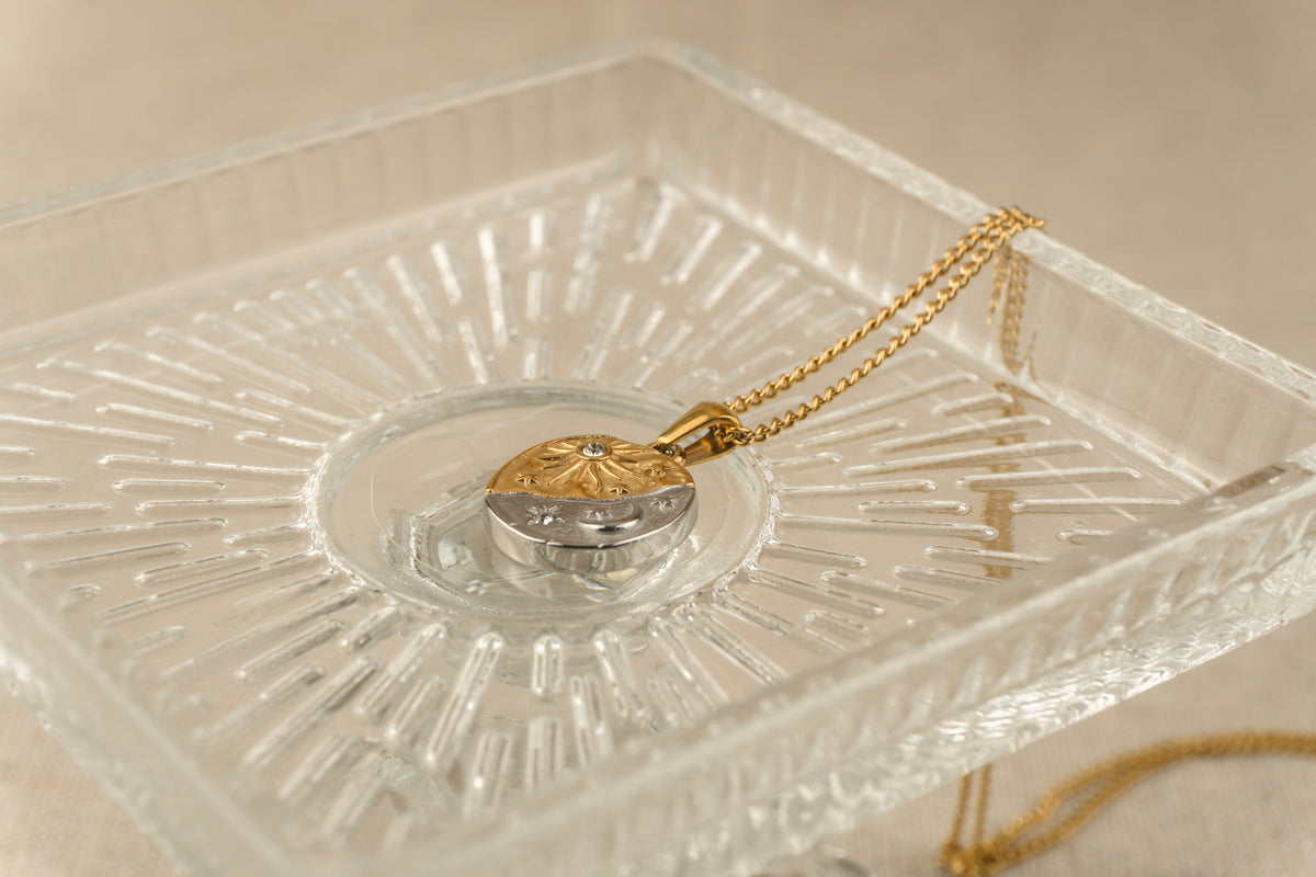 Detail van de celestial hanger met maan, zon en ster aan een fijne goudkleurige schakelketting