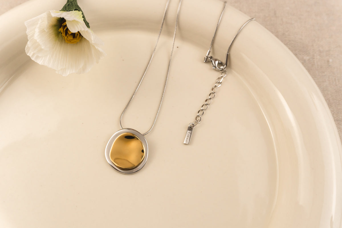 Zilverkleurige ketting met dubbele organische cirkelhanger aan een fijne schakelketting