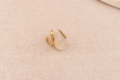 Goudkleurige ring met ronde crèmekleurige harsknop, op witte achtergrond