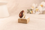 Goudkleurige ring met ovale bruine harsknop, op witte achtergrond