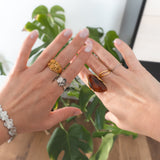 Goudkleurige ring met ovale bruine harsknop, op witte achtergrond
