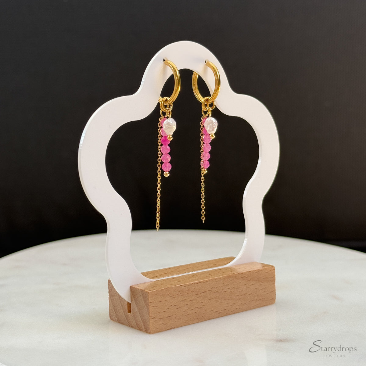 Detail van fuchsia hoop oorbel met roze toermalijn