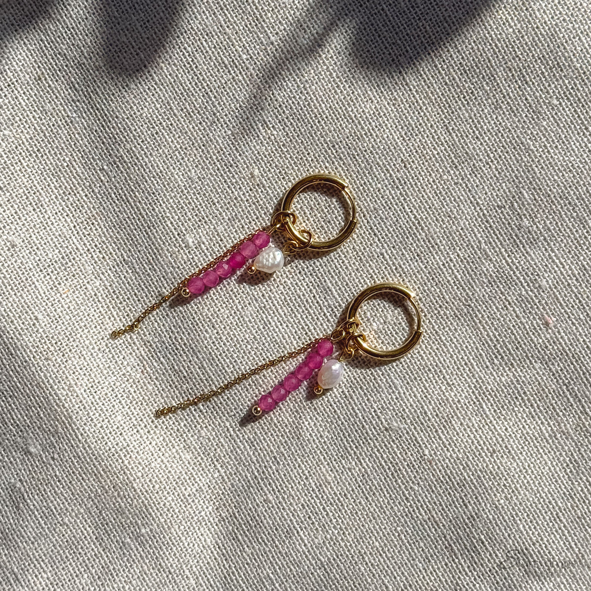 Detail van fuchsia hoop oorbel met roze toermalijn