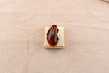 Goudkleurige ring met ovale bruine harsknop, op witte achtergrond
